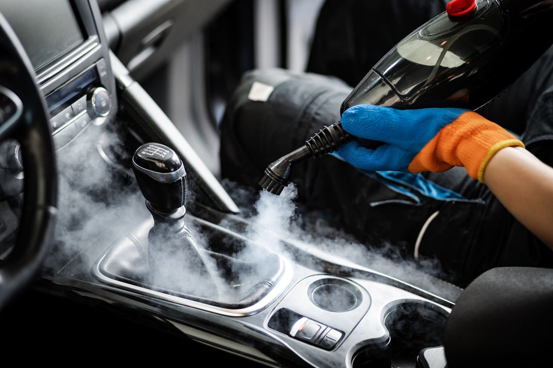 Steam cleaning a car interior to remove dirt and grime in a detailed auto detailing session